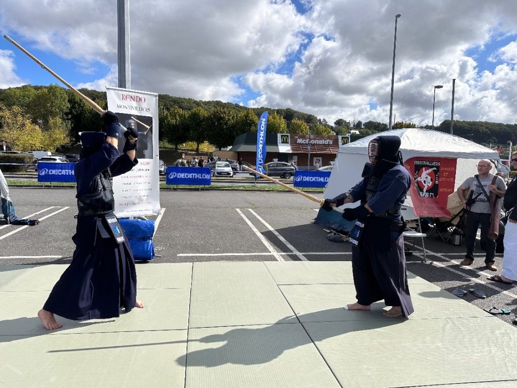 Deux kendoka en armure (bogu) en combat au shinai devant le public de Vitalsport