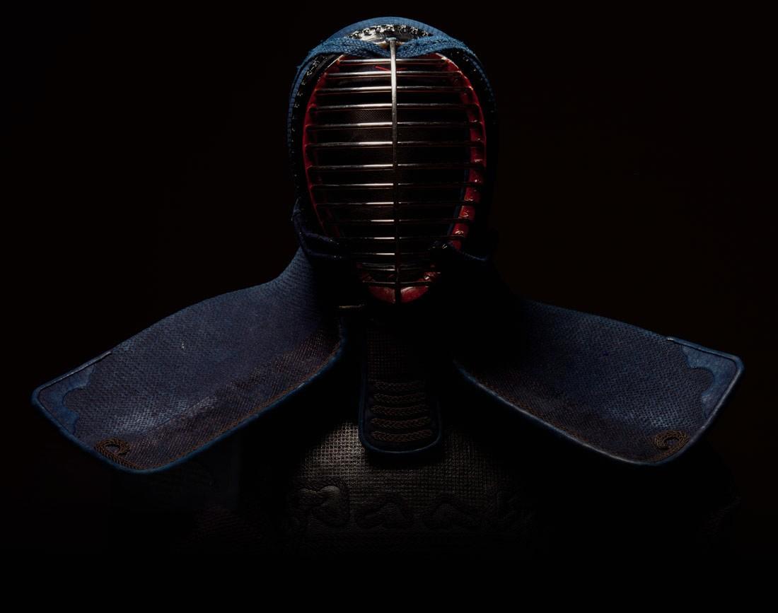 Casque et plastron d'une armure de kendo photographiés sur fond noir